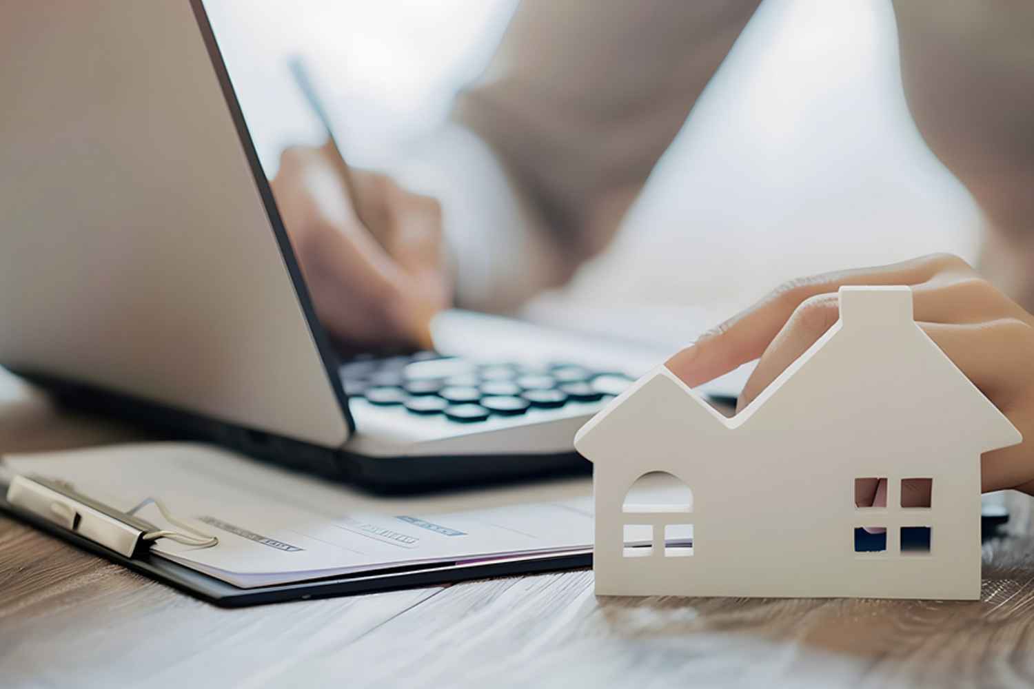 Person bearbeitet Akten, Modell eines Hauses im Vordergrund