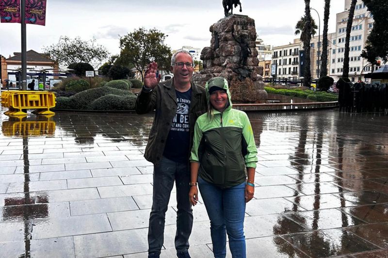 Mitarbeiter stehen im Regen vor einer Statue